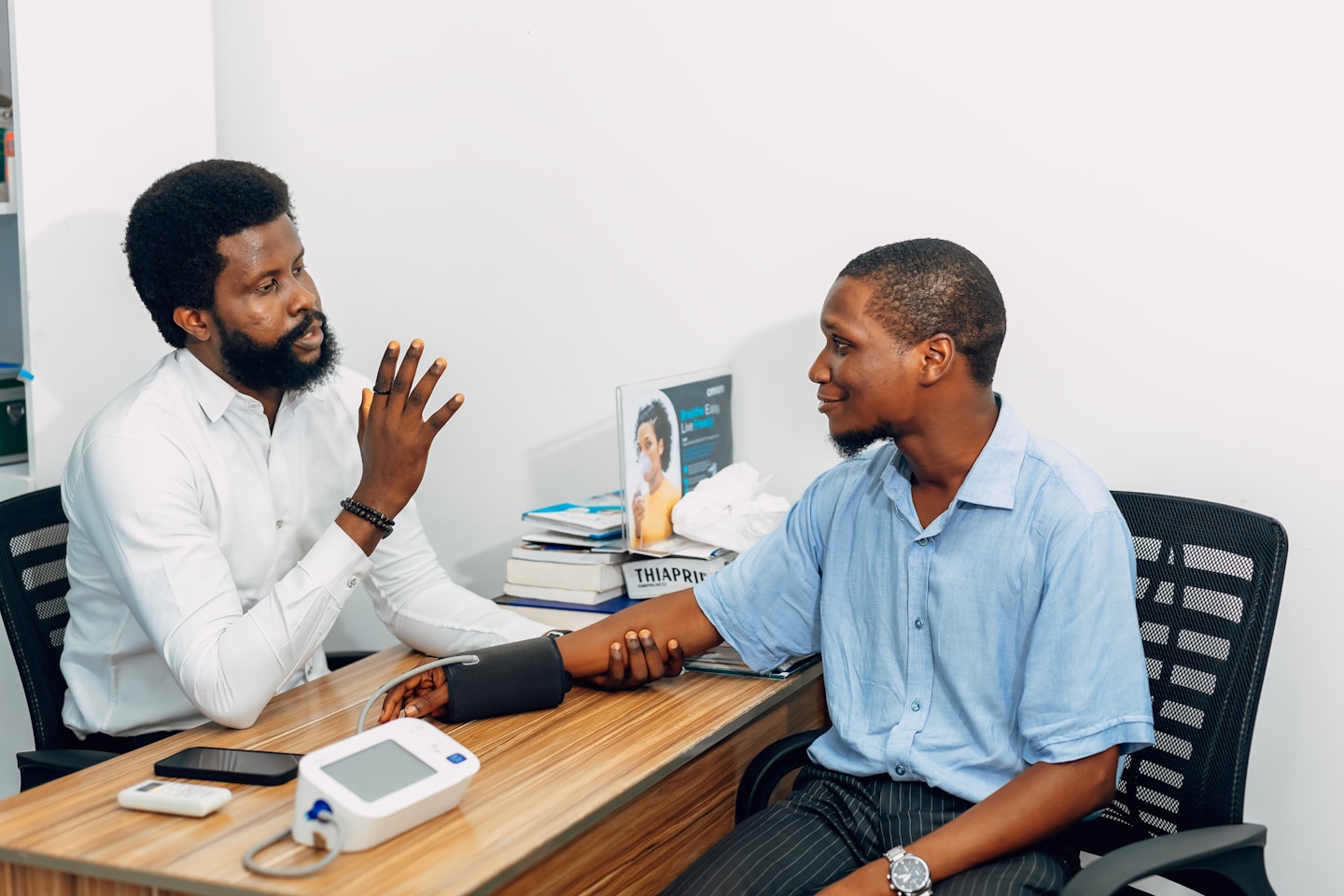 A doctor and patient are sitting across from each other at a desk. Find more afro-centric images at www.ninthgrid.com