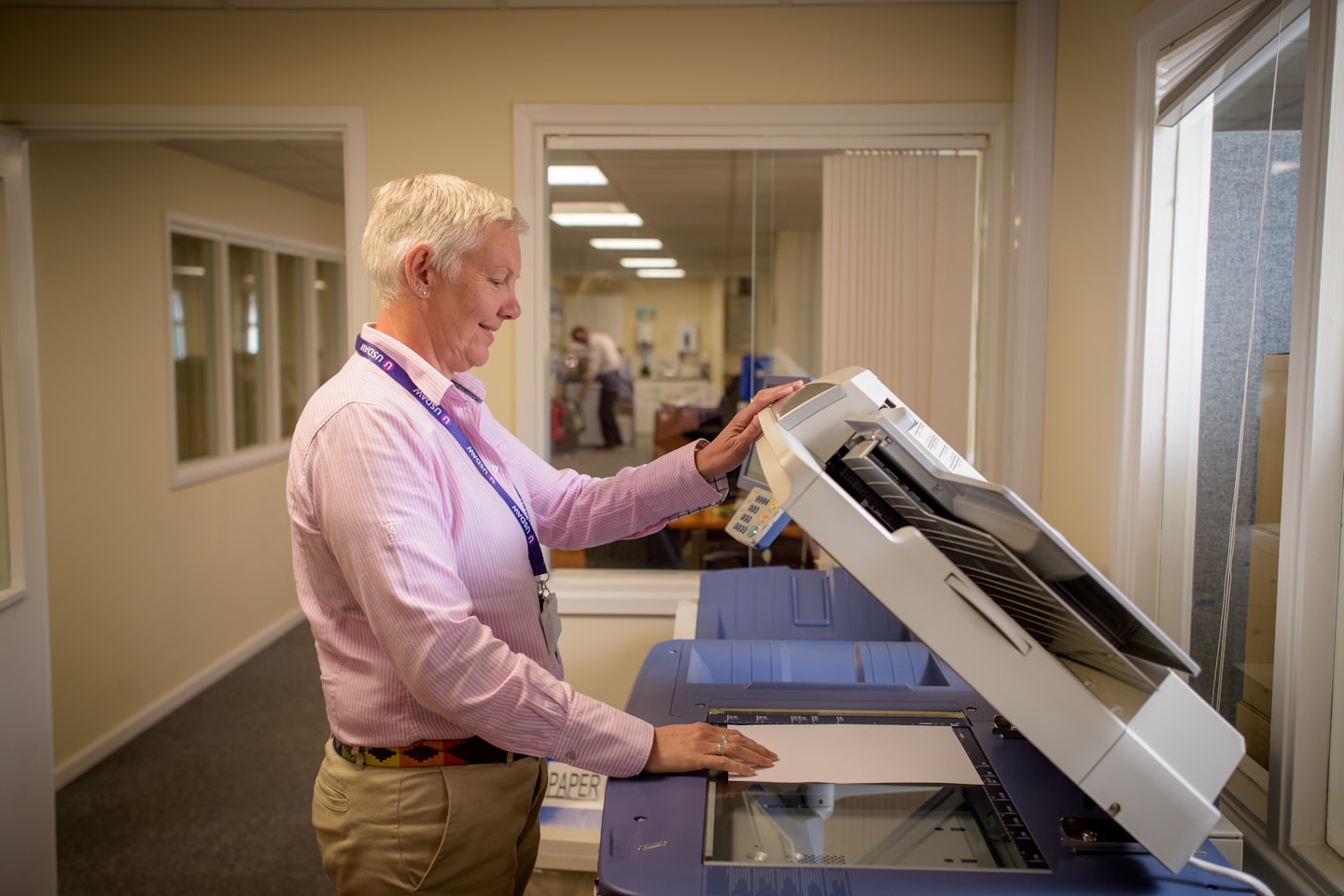 Older woman photocopies paper in an office