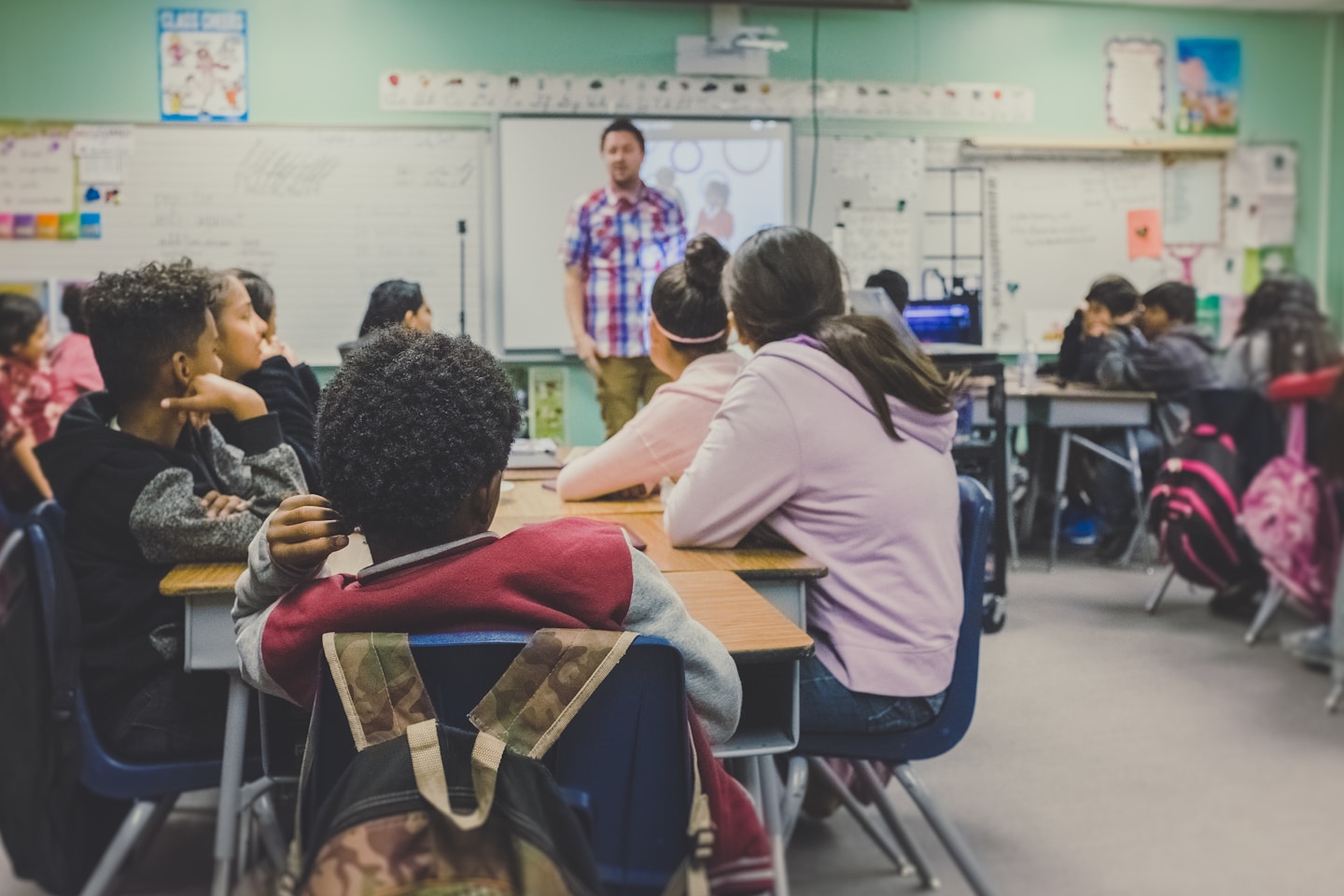 students in classroom with teacher presenting